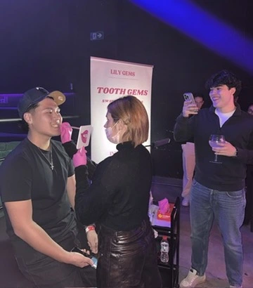 Carlota colocando gemas dentales en evento nocturno con el stand de Lily Gems